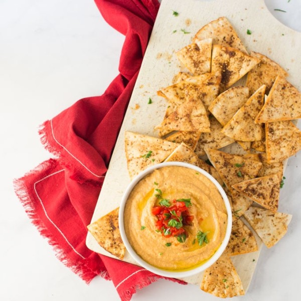 roasted red pepper hummus with homemade pita chips on white background