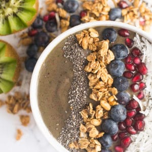 smoothie bowl topped with berries, chia seeds, coconut, and granola