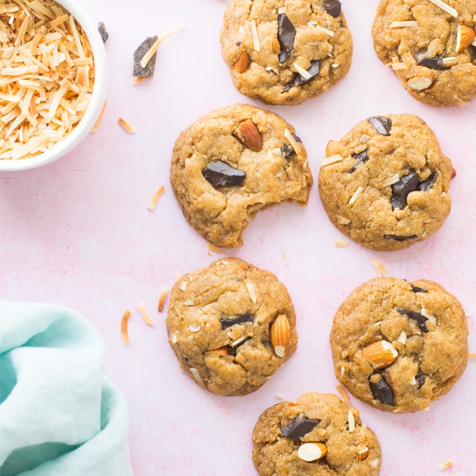 vegan chocolate chip cookies with almonds and coconut on pink background