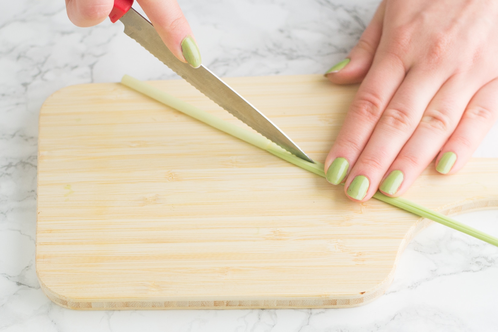 hand cutting lemongrass on wooden cutting board