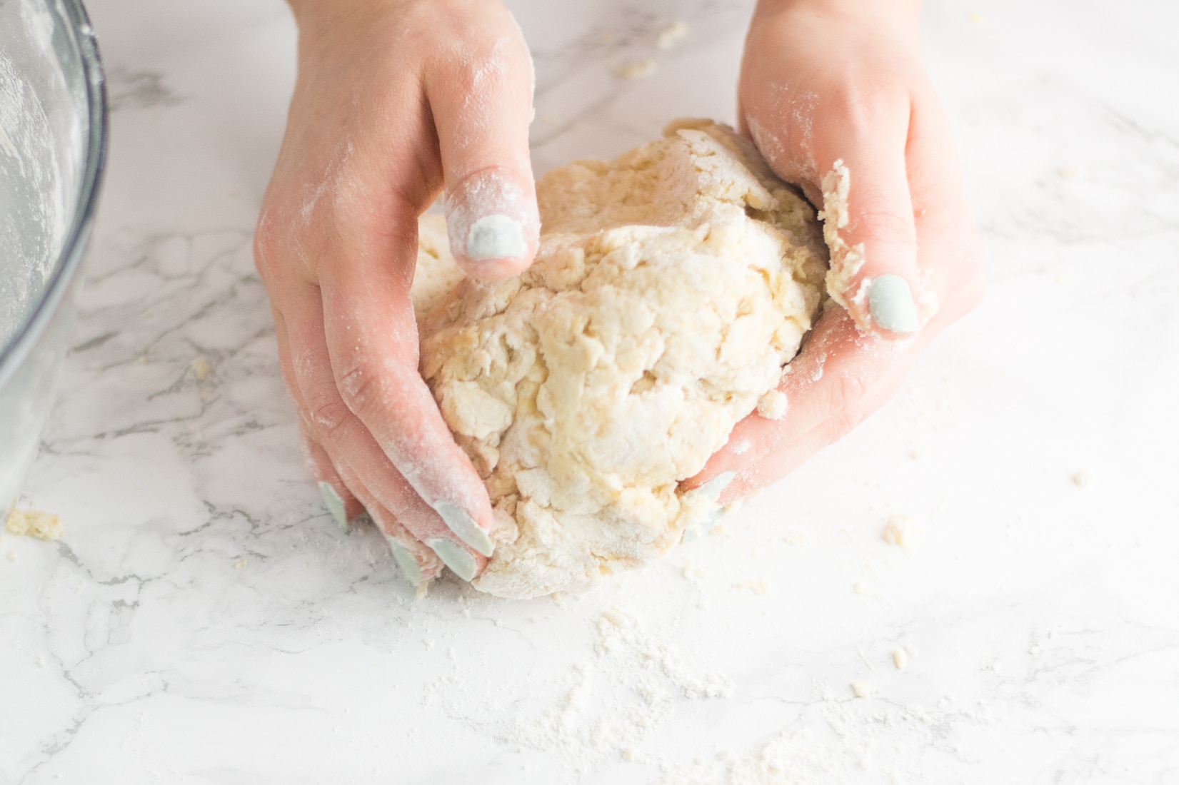 hands kneading dough on marble counter