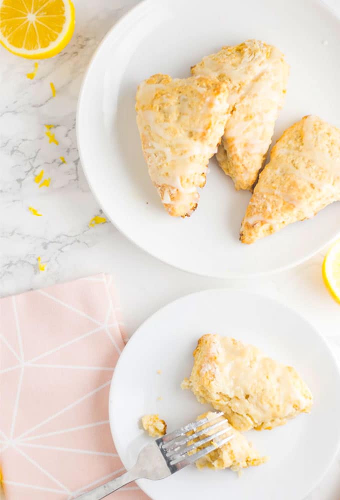 two plates of vegan lemon scones with pink napkin and lemon slices