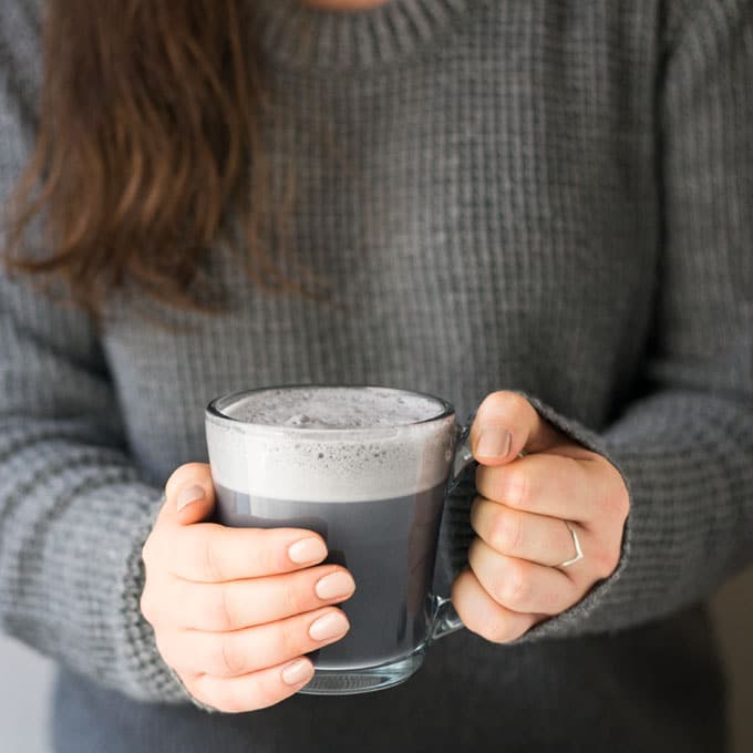 girl holding activated charcoal latte