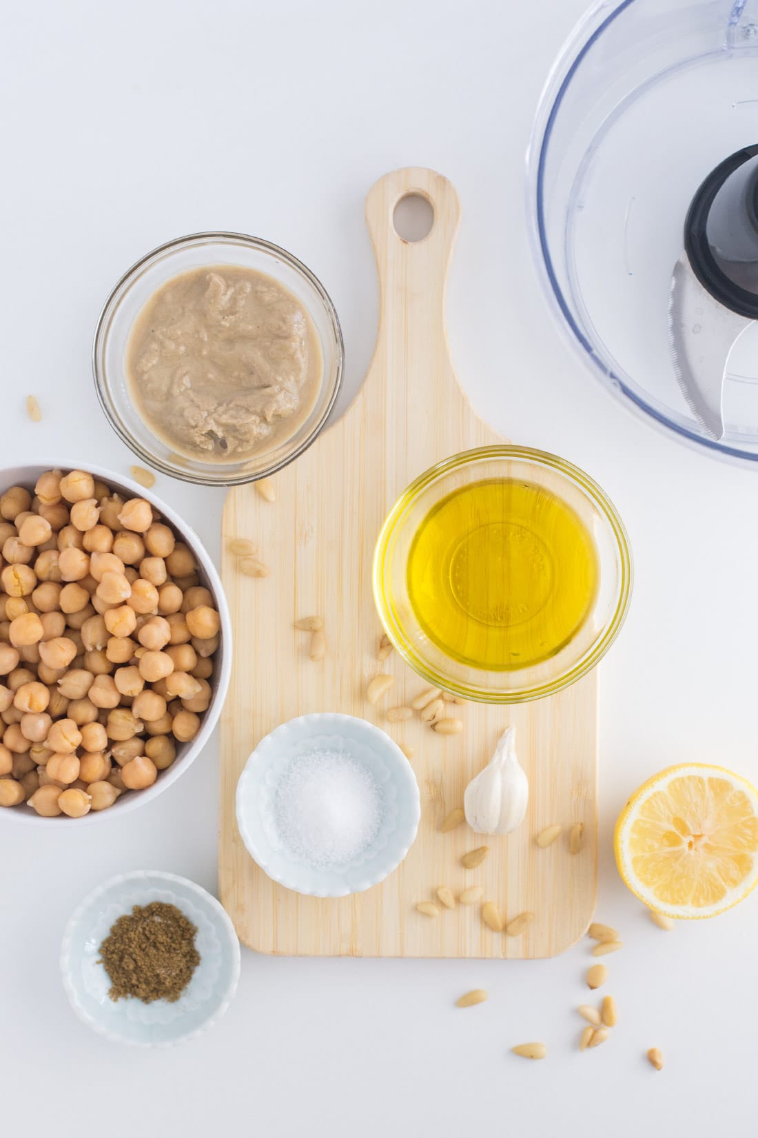 chickpeas, olive oil, tahini, salt, garlic, and lemon on white background