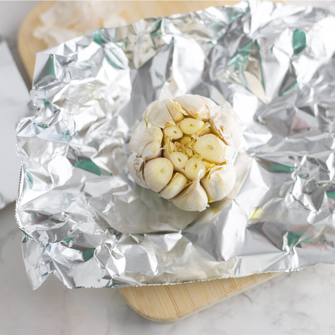 garlic bulb with olive oil on sheet of aluminum foil