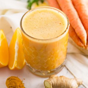 orange smoothie with prange slices, carrots, ginger, and turmeric