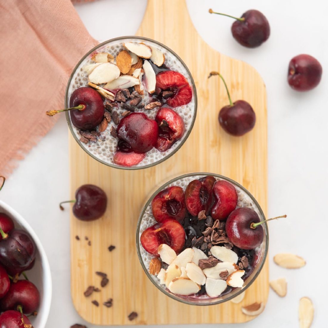 overhead view of chocolate cherry chia pudding cups on a board with cherries