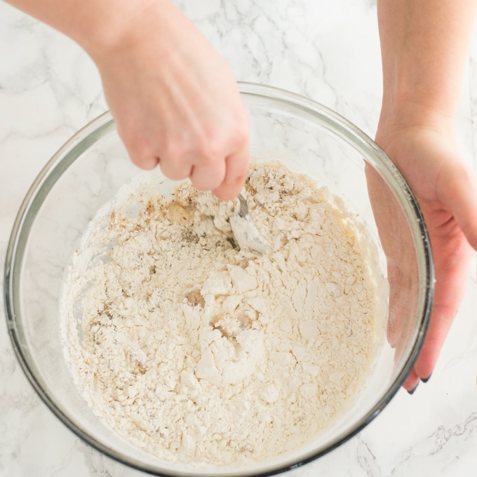hands mixing cake batter in glass mixing bowl