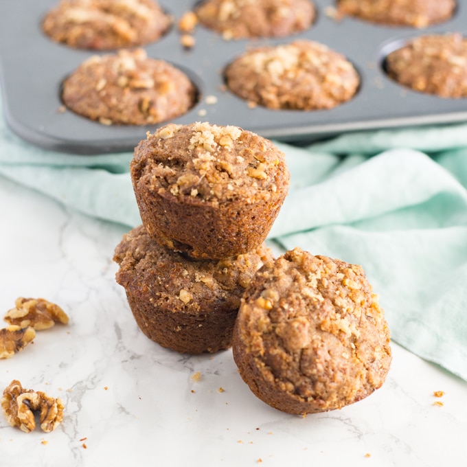 vegan banana muffins with walnuts on marble counter with muffin tin on light blue napkin