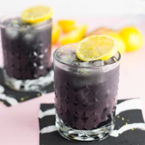 activated charcoal lemonade made with lemon juice, charcoal powder, and maple syrup. garnished with fresh lemons