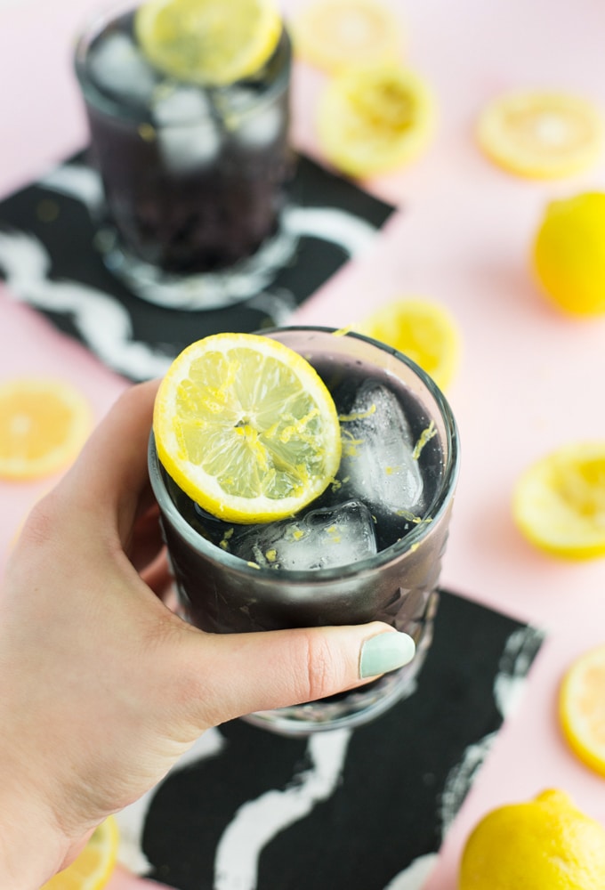 hand holding glass of activated charcoal lemonade