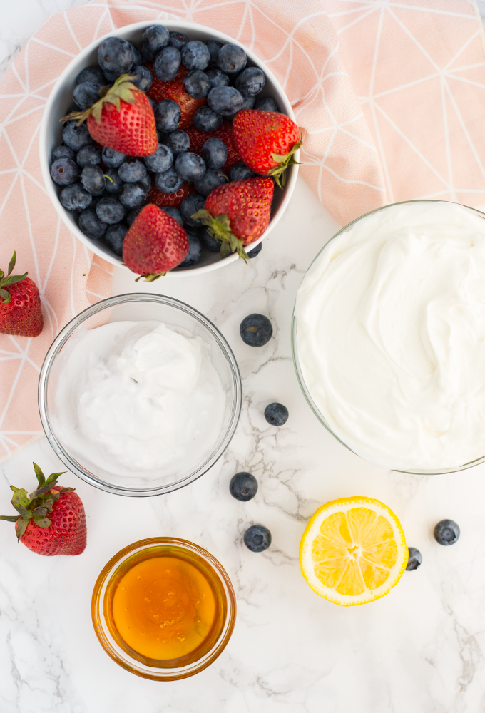 berries, greek yogurt, coconut milk, honey, and lemon on marble background