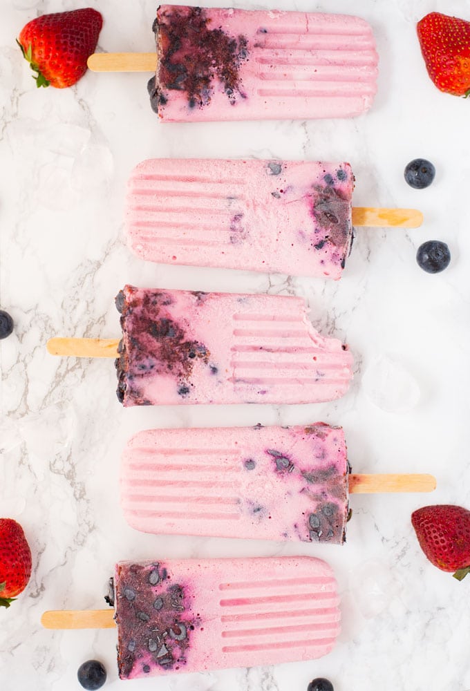 yogurt berry popsicles on marble counter in a line