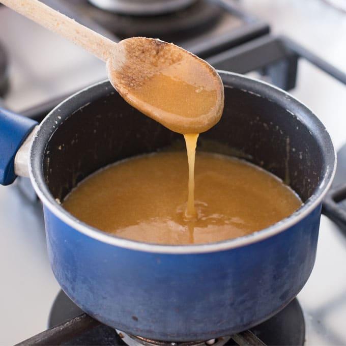 spoon drizzling caramel sauce over pot