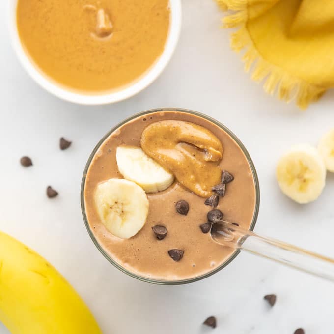chocolate peanut butter banana smoothie topped with banana slices, peanut butter, and chocolate chips.