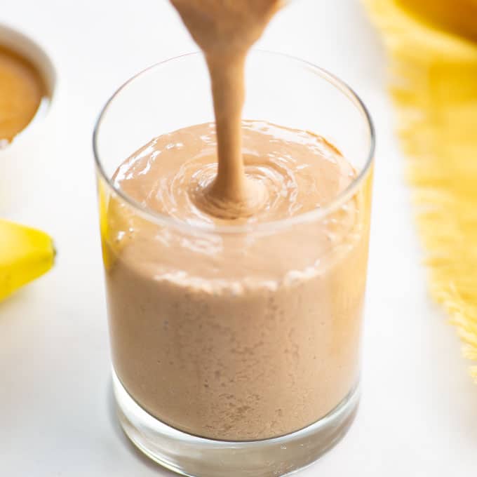 pouring a chocolate peanut butter smoothie into a glass