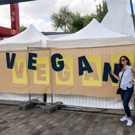 girl standing in front of vegan sign at smmmile festive in paris, france
