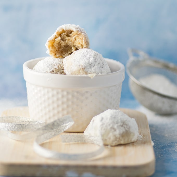 vegan russian tea cakes in white dish on blue background