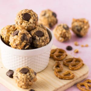 chocolate chip peanut butter energy bites with pretzels on pink background