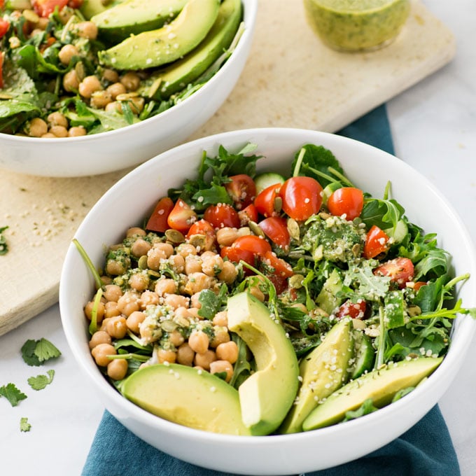 vegan salad with chickpeas, tomatoes, and avocado in white bowl