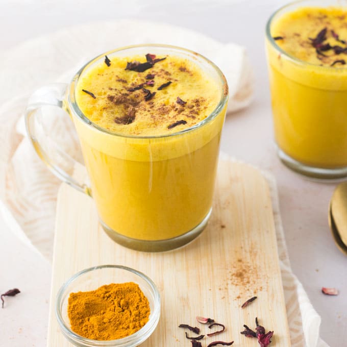 turmeric latte with rose petals on a wood board