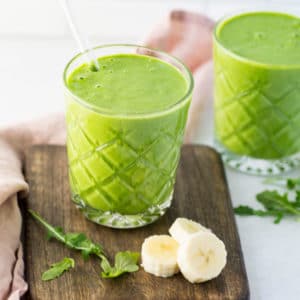 green smoothie on wooden board with bananas and spinach