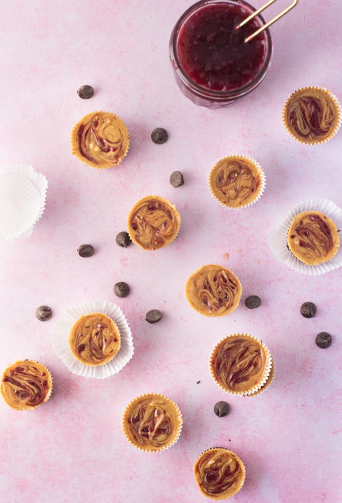 homemade peanut butter cups with jelly swirl on pink background with chocolate chips