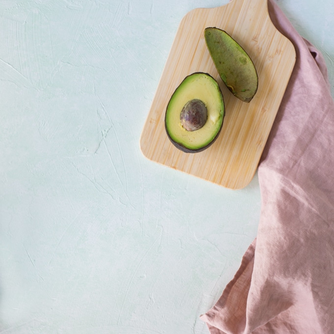 avocado on mint background with pink napkin
