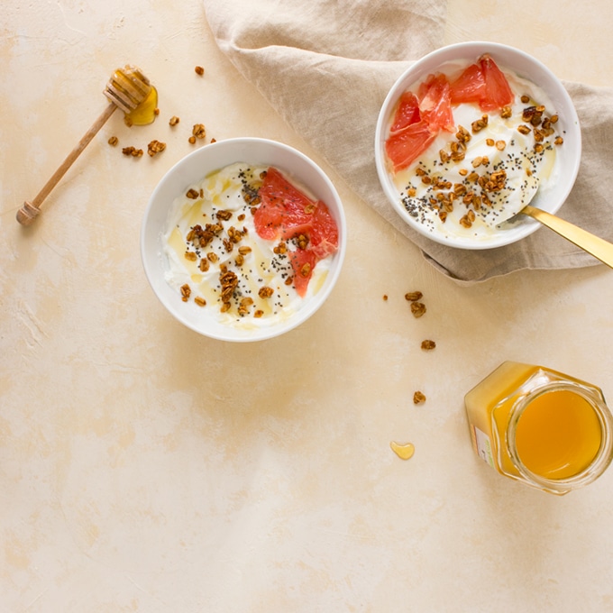 yogurt bowls with grapefruit and honey on cream background