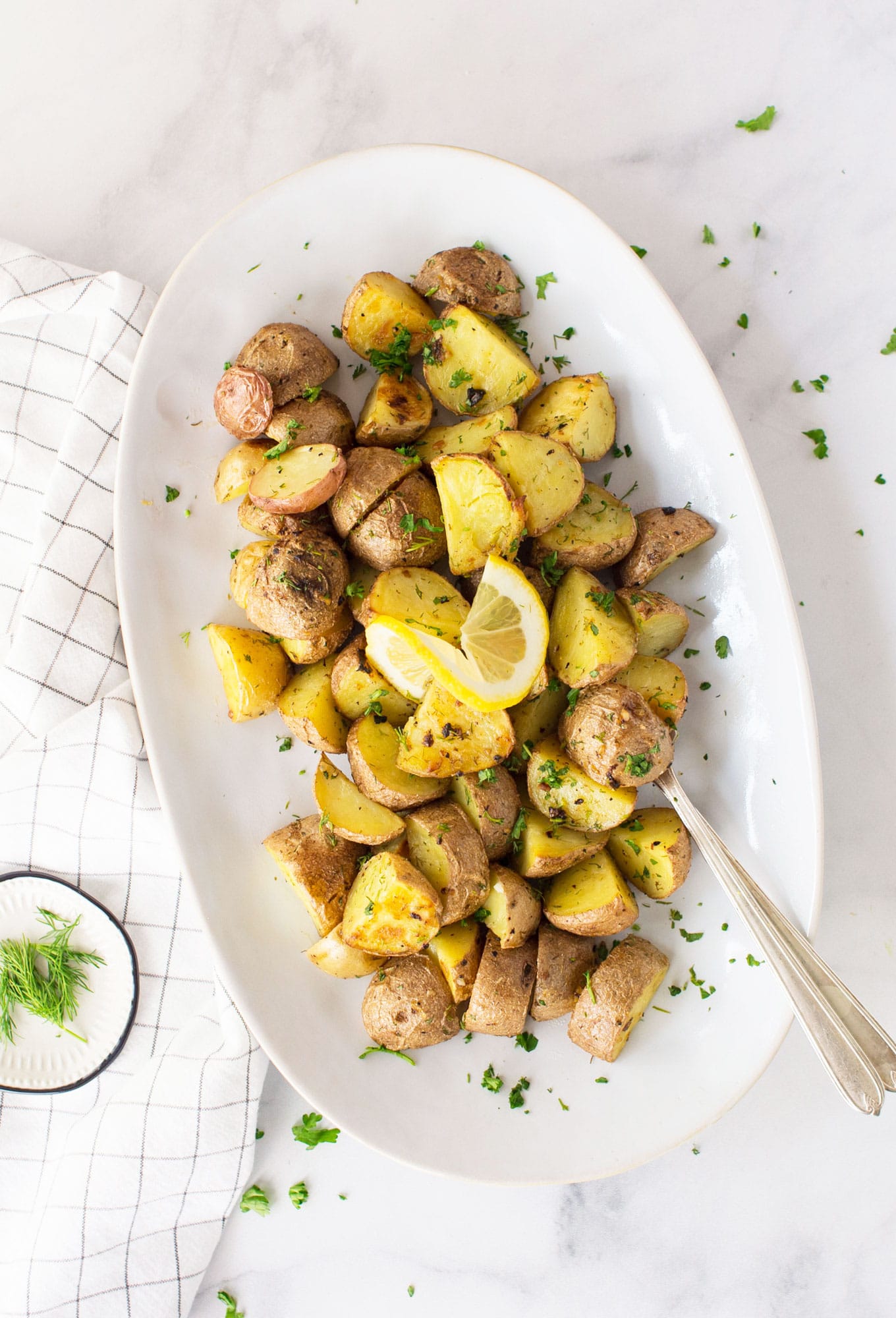 serving platter of roasted red potatoes with lemon and dill