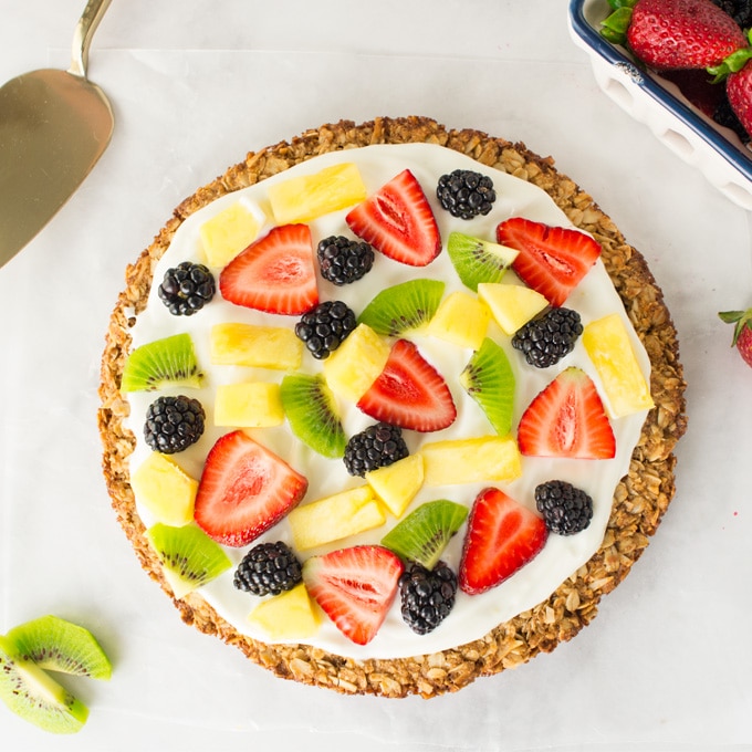 healthy fruit pizza with granola crust topped with greek yogurt and fresh fruit