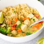 vegan thai green curry in bowl with brown rice, veggies, tofu, and lime
