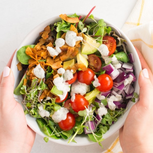 hands holding vegan cobb salad