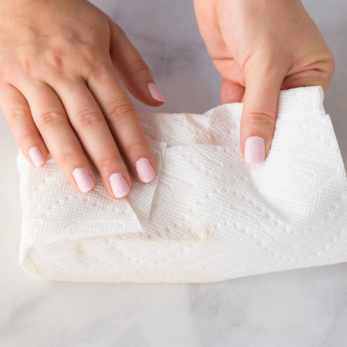 hands wrapping tofu in paper towels to press tofu