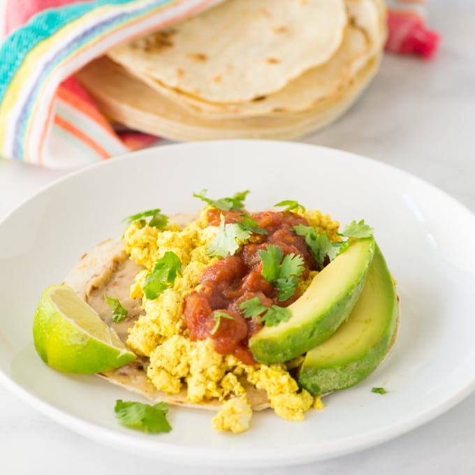 vegan huevos rancheros on a plate with salsa and avocado