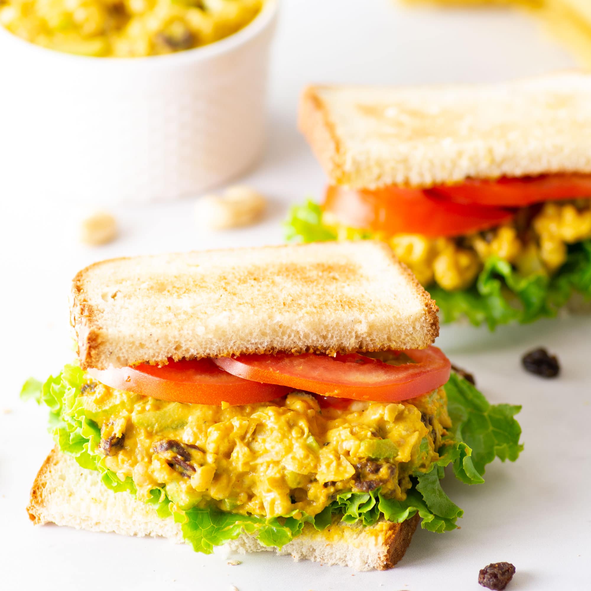 vegan chickpea salad sandwich on marble background with lettuce and tomato