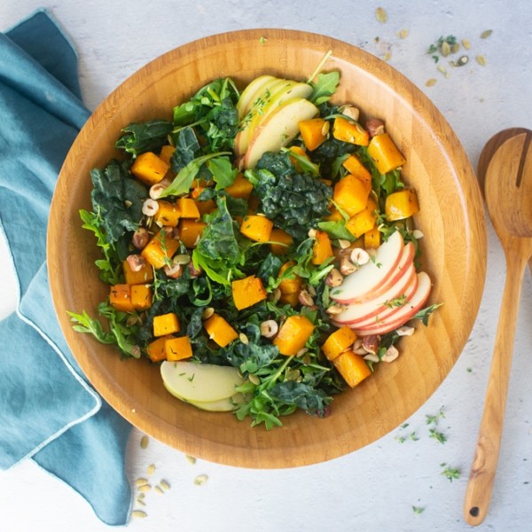 salad with kale, apples, squash, and hazelnuts in wood salad bowl