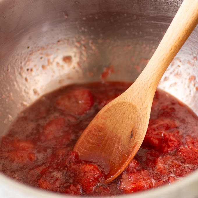 strawberry compote in sauce pan with wooden spoon