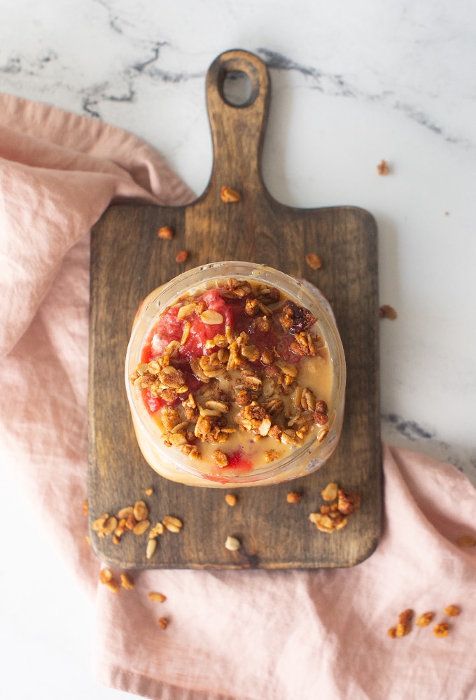 peanut butter and jelly overnight oats with granola on wood board