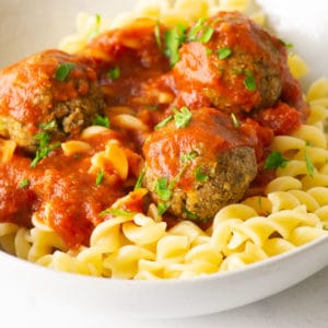 close up of vegan tofu meatballs on pasta with marinara sauce