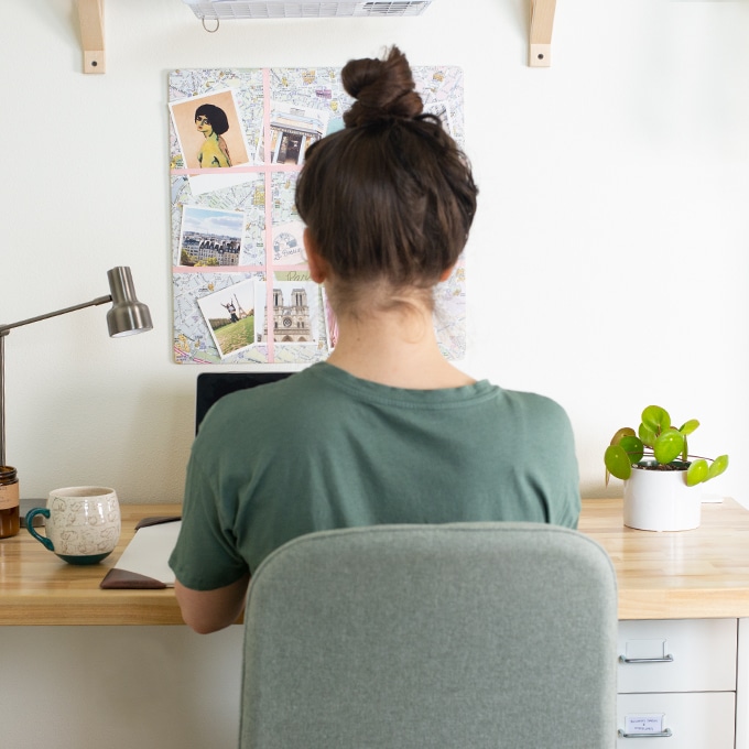 girl with hair in bun and wearing green shirt working at her desk