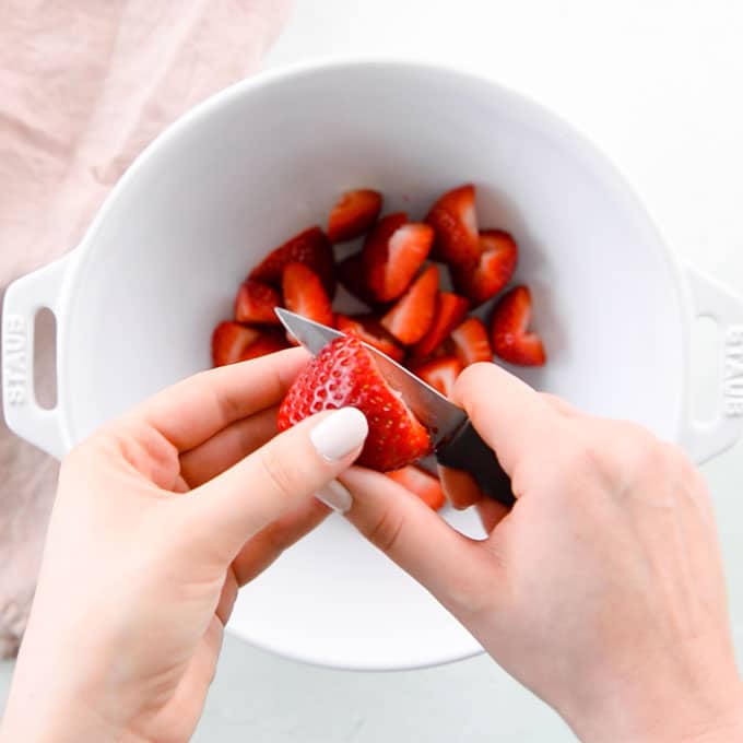hands cutting strawberry with paring knife