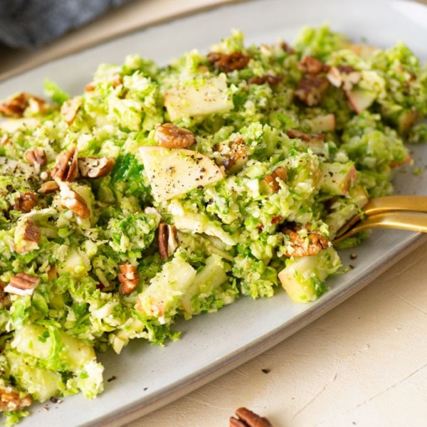 shaved brussel sprout salad topped with pecans and apples