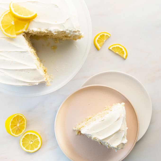 overhead view of lemon cake on a cake stand and a dessert plate