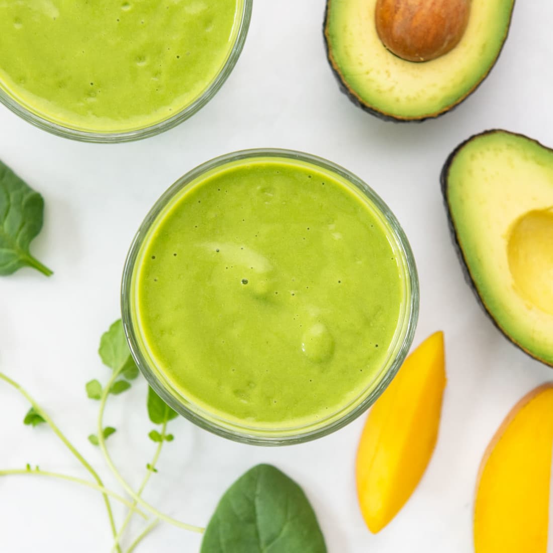 overhead view of green smoothie with mango, avocado, spinach, and watercress
