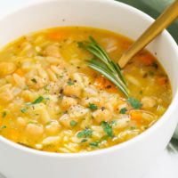 bowl of orzo lemon soup topped with black pepper and rosemary