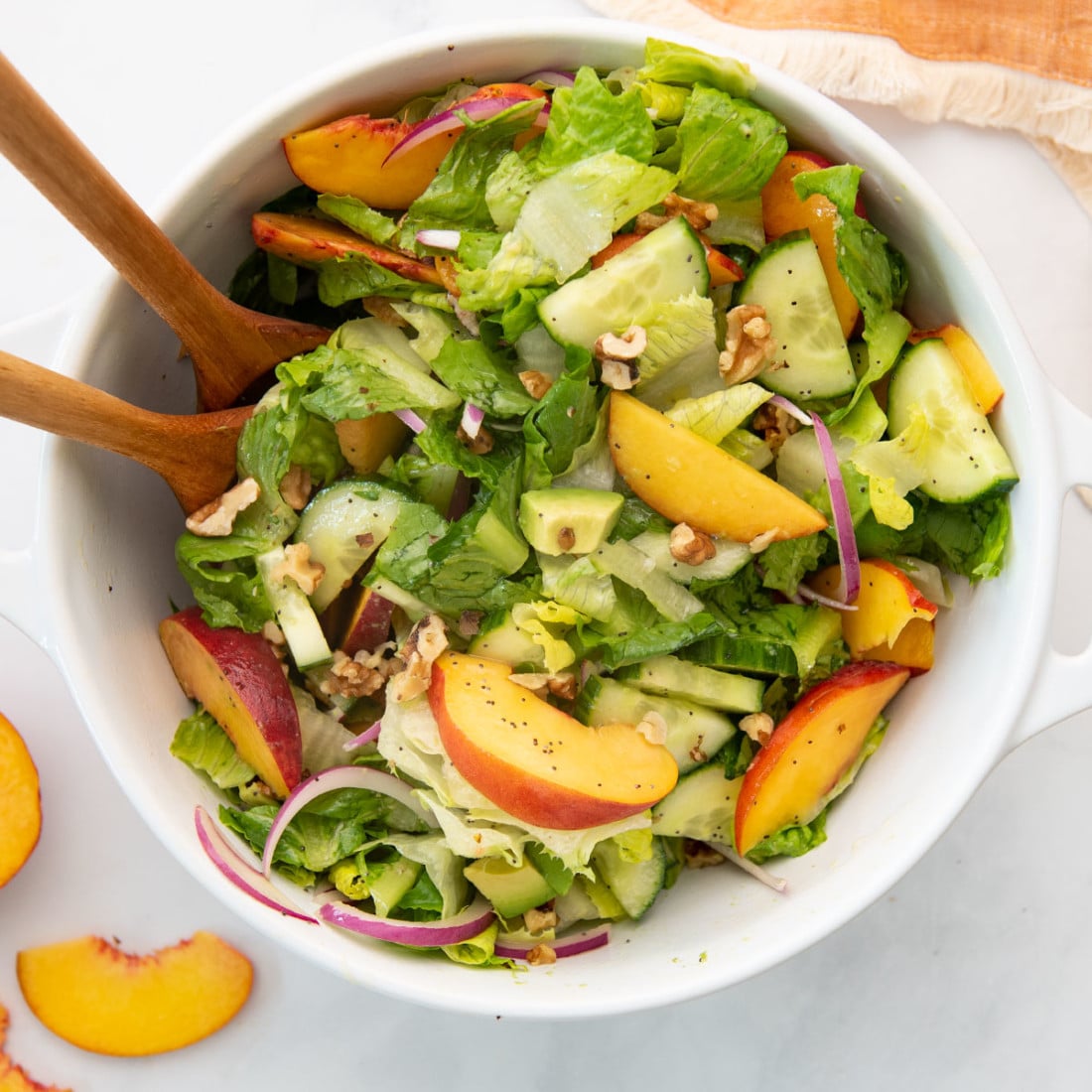 salad with romaine, peaches, red onion, cucumbers, walnuts, and avocado in salad bowl