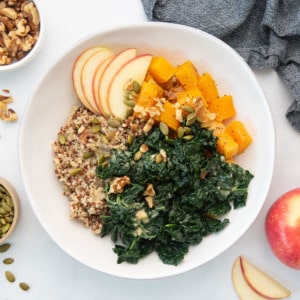 vegan grain bowl with quinoa, butternut squash, apples, kale, walnuts, and pepitas