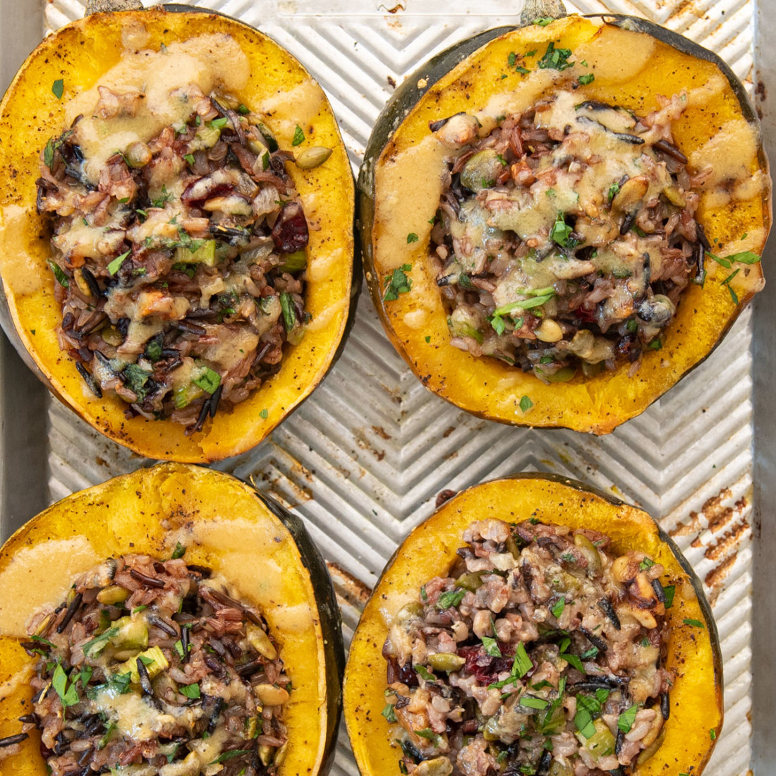top view of 4 halves of roasted acorn squash stuffed with rice and vegan ingredients on a baking sheet