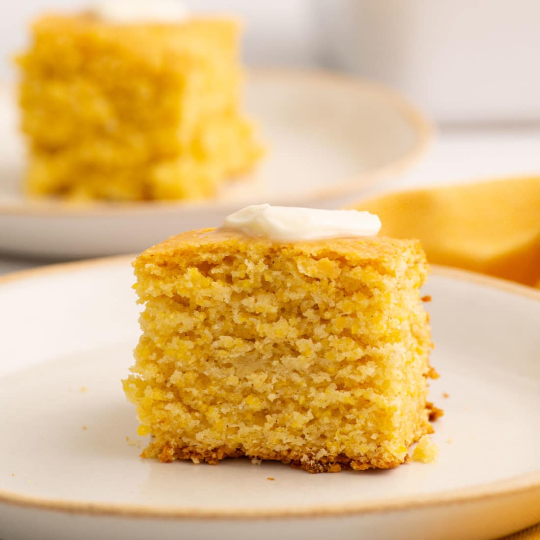 slice of baked dairy free eggless cornbread on a white plate side view
